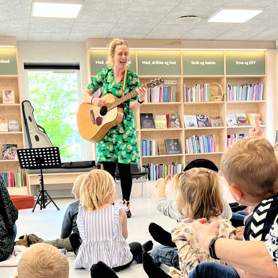 En kvinde med en guitar foran en gruppe børn