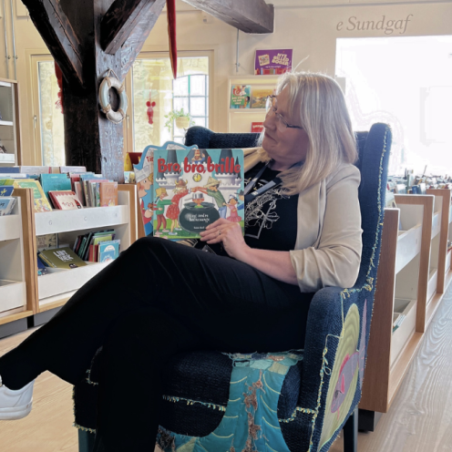Foto af bibliotekar, der sidder med børnebøger i en stol i børnebiblioteket